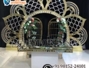 wedding reception stage backdrop, peacock theme wedding decor, golden wedding backdrop, floral wedding arch stage, luxury reception setup, engagement stage decoration, modern Indian wedding stage, bridal shower backdrop, couple seating decor, artificial flower arch, metal wedding backdrop, wedding photo booth frame, premium wedding decoration