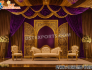 "Arabic theme golden open door style wedding stage backdrop with laser-cut panels, purple and gold drapery, royal sofa and chairs, and floral decorations – luxury wedding stage setup UK."