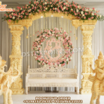 Classic Gujarati Style Roka Ceremony Stage Decor with golden carved pillars, floral arch, hanging Ganesha centerpiece, carved sofa, and elephant Ganesha statues.