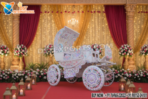 Grand Maharaja style moving wedding entrance carriage with handcrafted carvings, ornate wheels, and luxurious design, set on a decorated wedding stage with flowers and lights.
