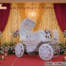 Grand Maharaja style moving wedding entrance carriage with handcrafted carvings, ornate wheels, and luxurious design, set on a decorated wedding stage with flowers and lights.