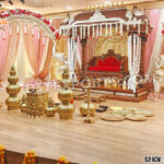 Grand Southern wedding stage setup with golden mandap, white elephant arch pillars decorated with flowers, and pink-golden drapes — perfect for traditional South Indian marriage ceremonies.